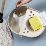 Adding cleaning powder to a mop bucket.